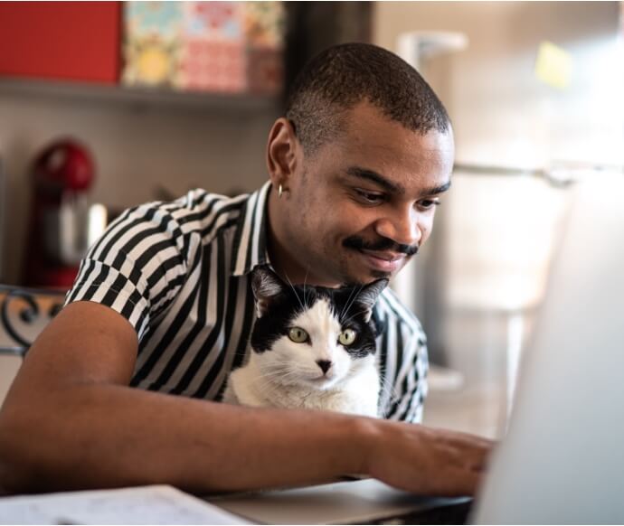 Homem a usar portátil enquanto segura um gato