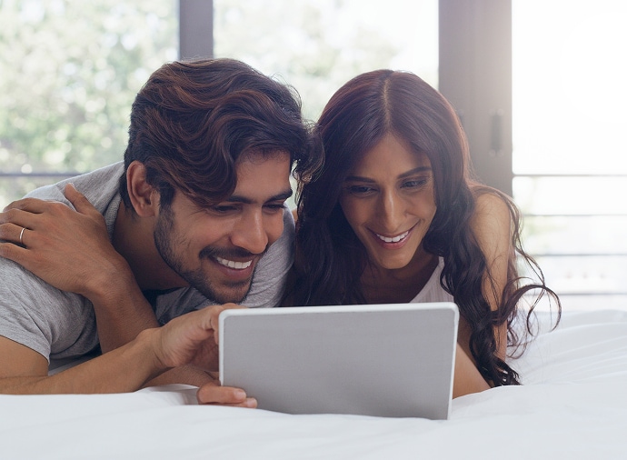 Homem e mulher a rir enquanto olham para um tablet