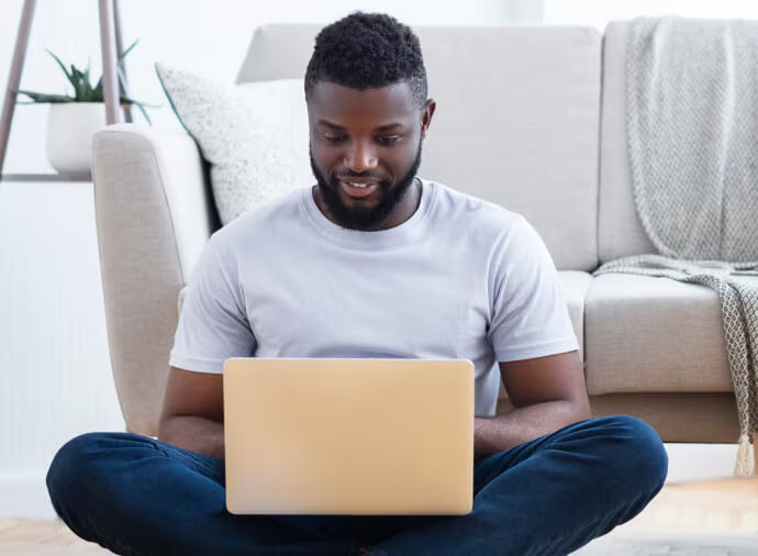 Homem sentado a utilizar um computador portátil