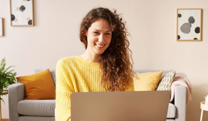 Senhora a sorrir e a usar um computador portátil que está a iniciar o Norton Safe Search.