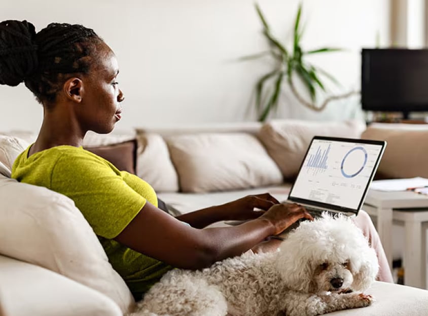 Mulher sentada com um cão enquanto trabalha num portátil